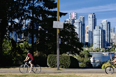 A happy cyclist wearing a helmet cruising along the Rhine river path with the city skyline in the background.
