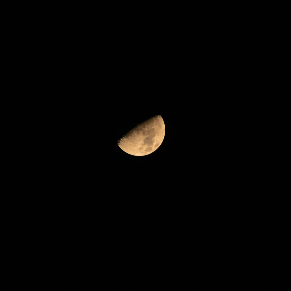 a half moon is seen in the dark sky