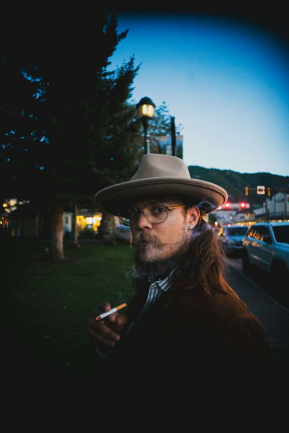 a man with a hat and glasses smoking a cigarette