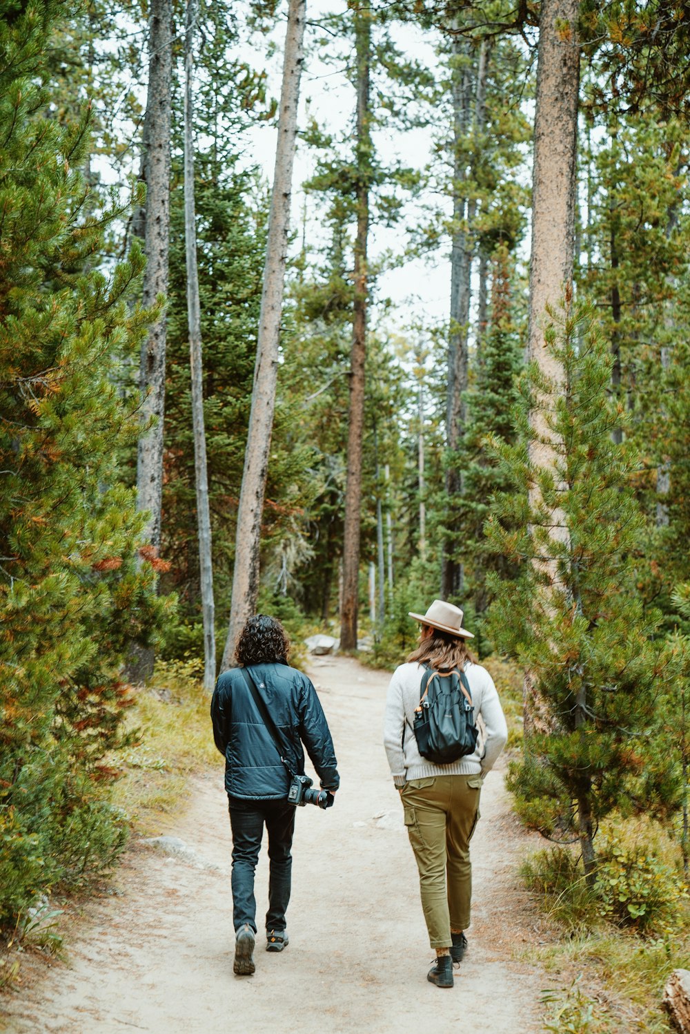 two people walking down a path in the woods