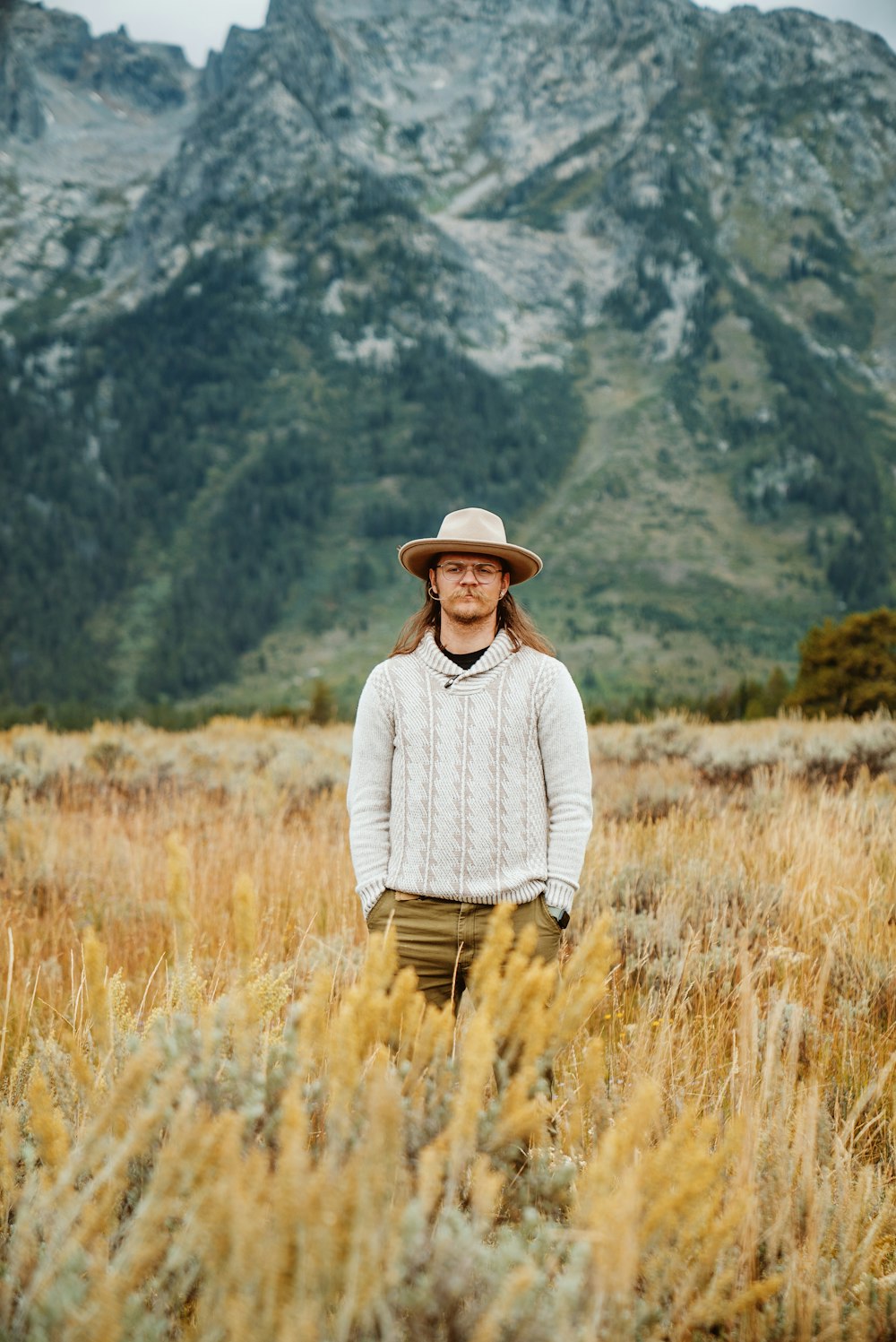 a man standing in a field with a mountain in the background