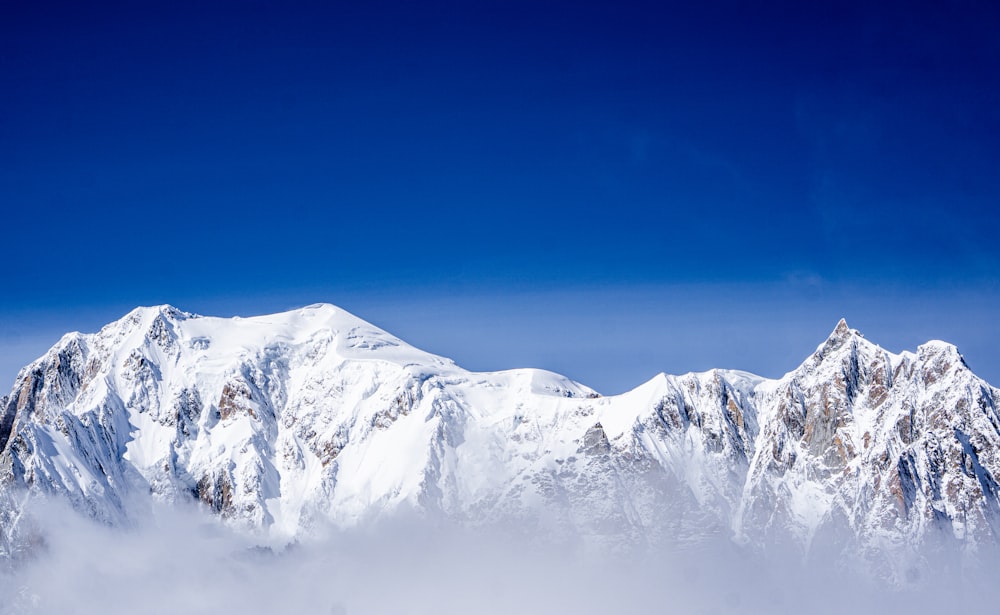 a snow covered mountain range with a blue sky in the background