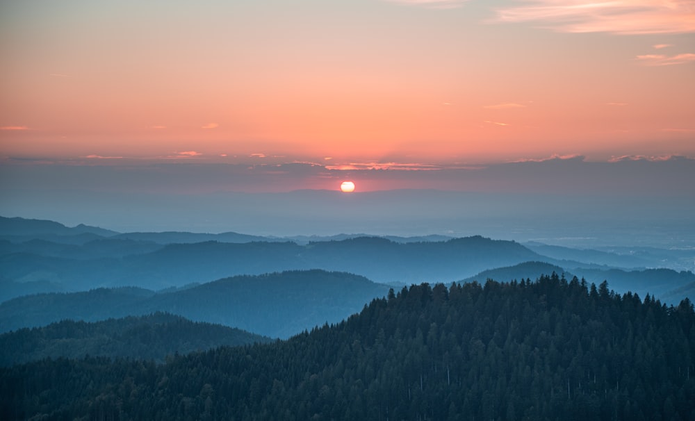 the sun is setting over a mountain range