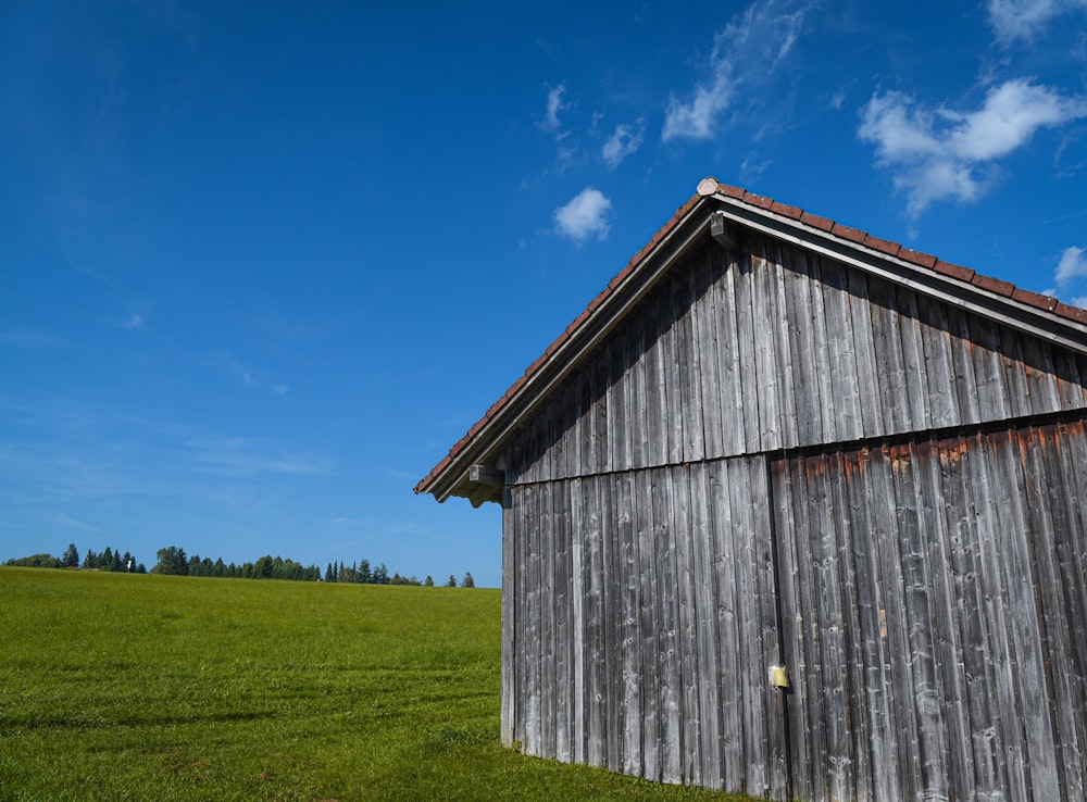 a wooden building sitting in a green field