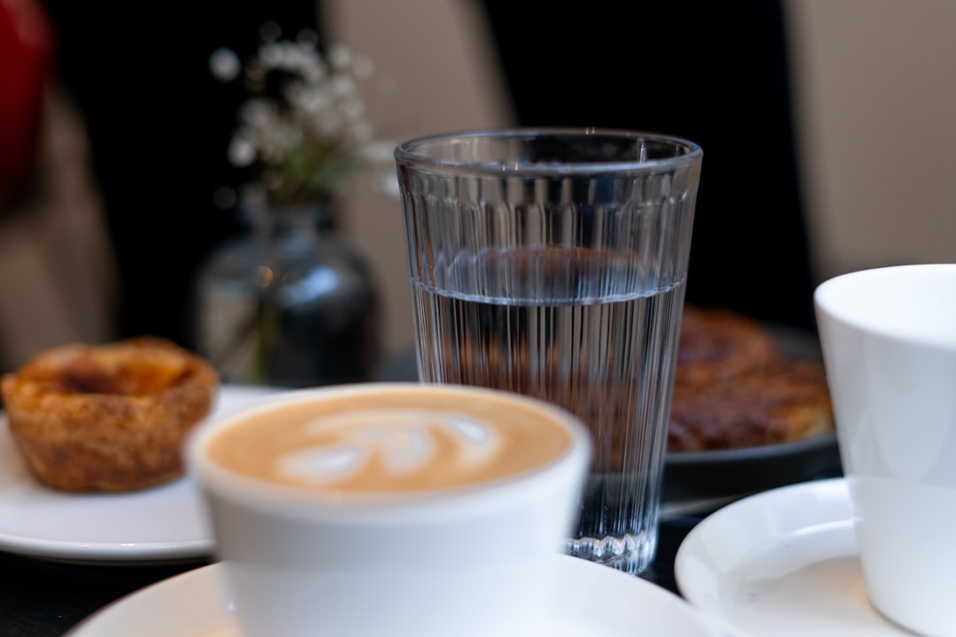 a cup of coffee sitting on top of a white plate,