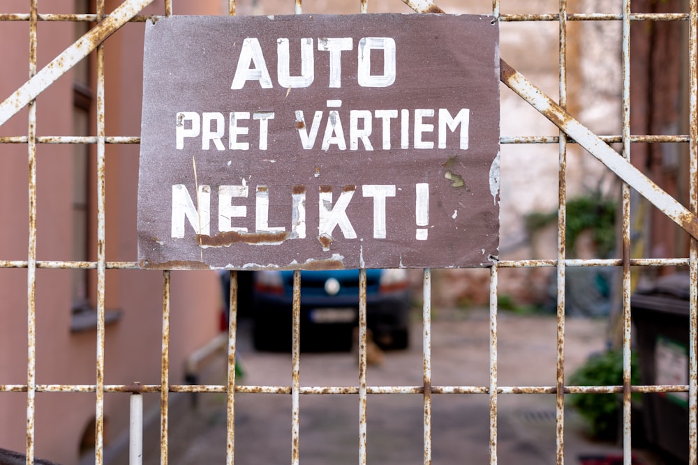 a sign on a gate that says auto pret vartiem nelkt