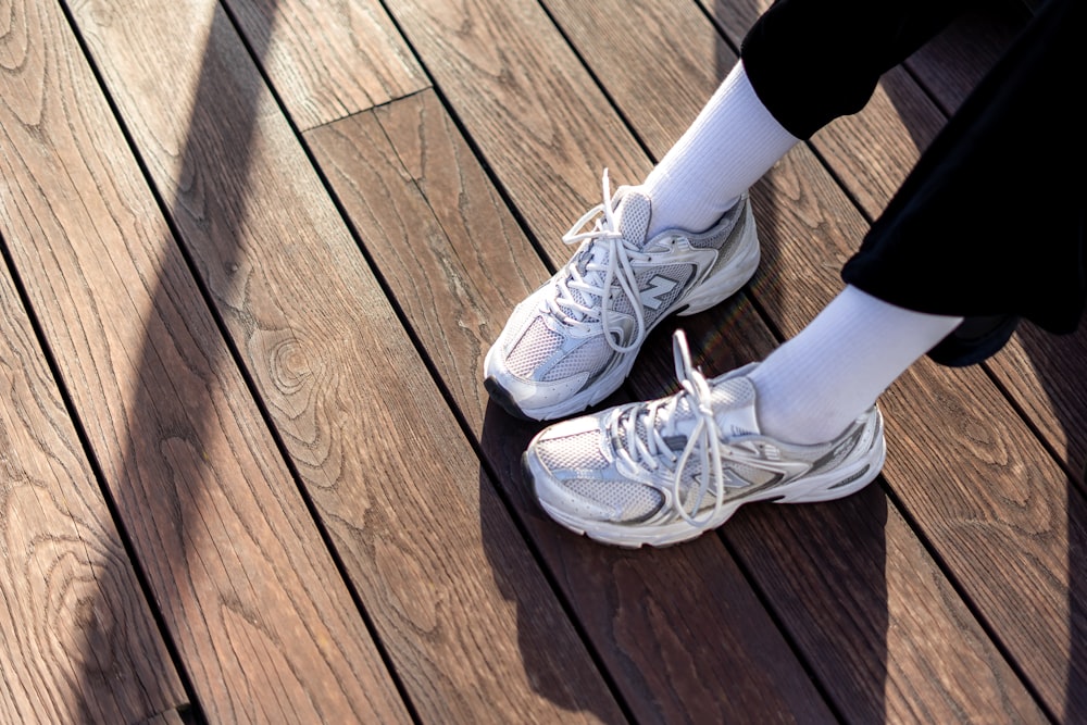 a pair of white shoes sitting on top of a wooden floor