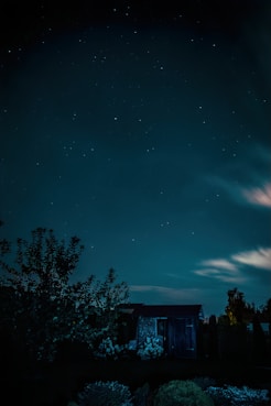 a night sky with stars and clouds over a building