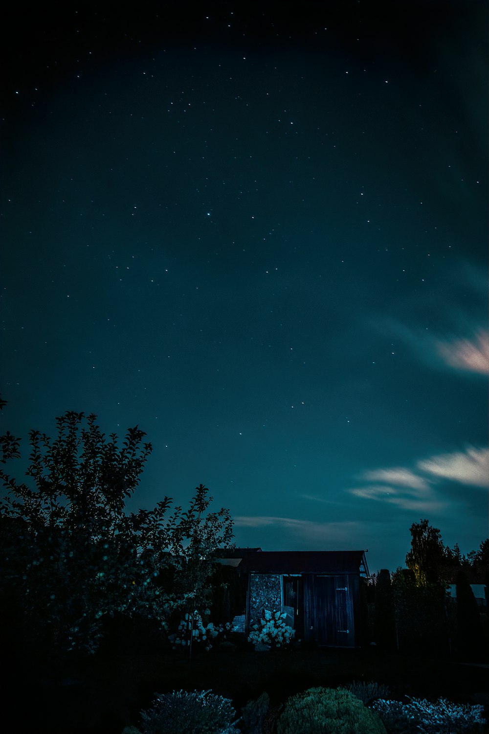 a night sky with stars and clouds over a building