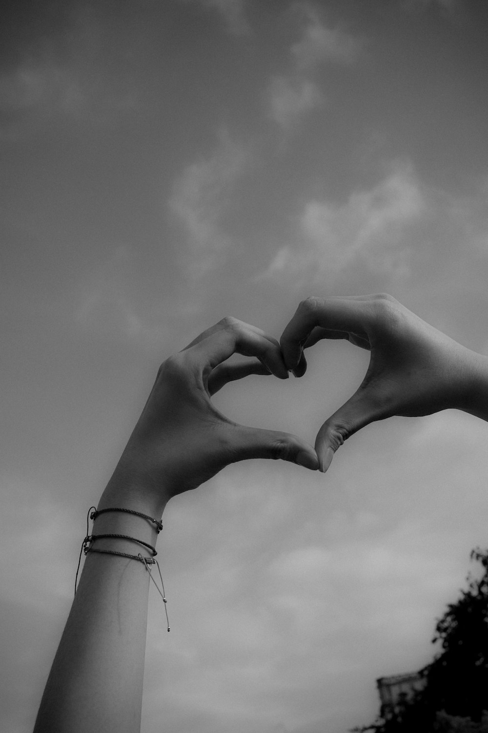 a black and white photo of two hands making a heart