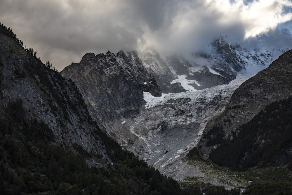 a snow covered mountain range under a cloudy sky