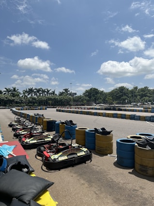 A kart racer analyzing data on a tablet beside the kart in a sunny outdoor track setting.