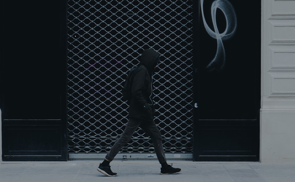 a man walking down a street past a building