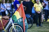 Close-up of a colorful bike with a double-sided flag banner trailing behind on a sunny day.