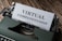 An old-fashioned typewriter with the words 'Virtual Companionship' typed on a sheet of paper. The image includes a green typewriter and a wooden surface background.