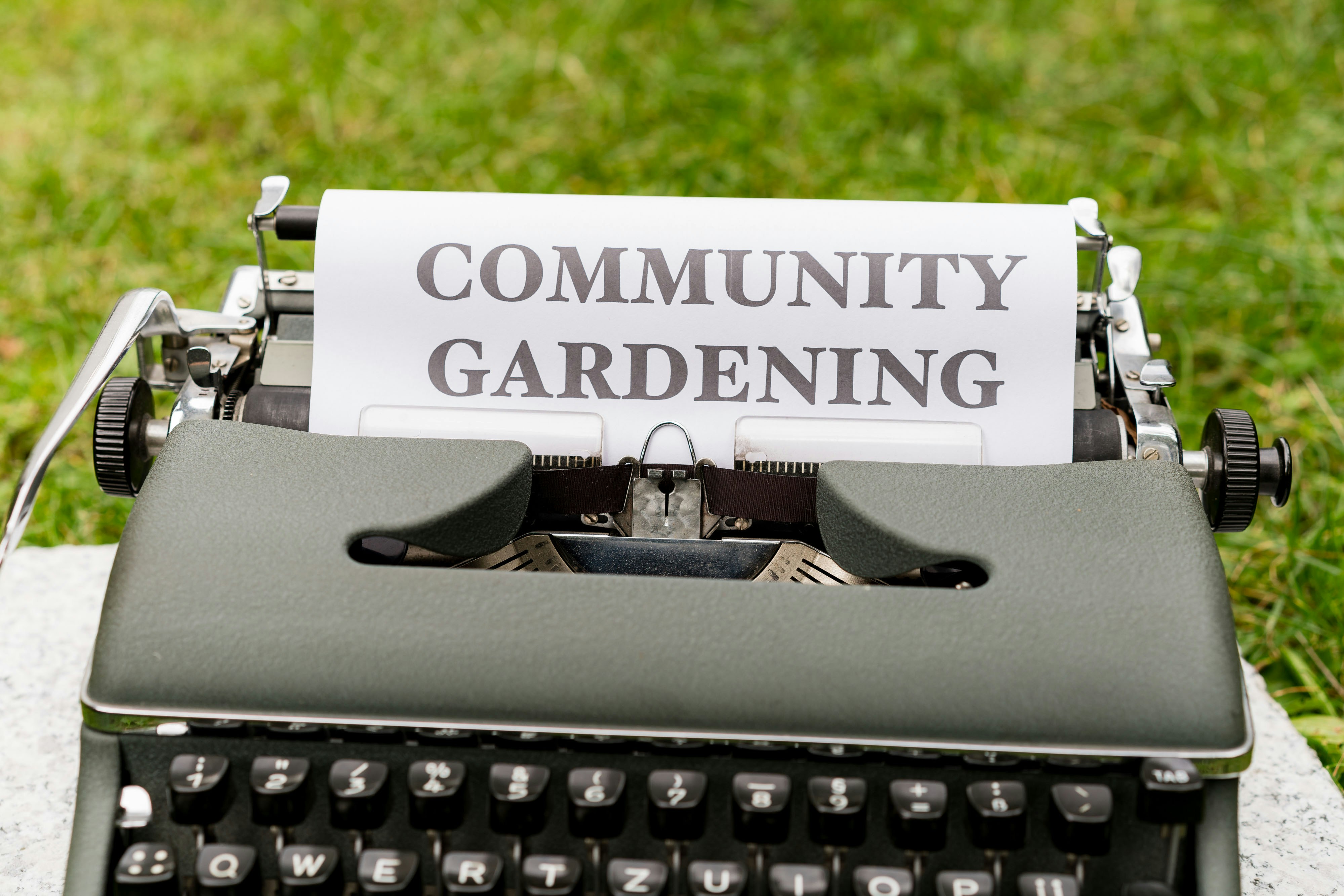 a close up of a typewriter with a paper that reads community gardening