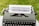 An old-fashioned typewriter is placed on a grassy surface with a sheet of paper inserted into it. The paper features the words 'NEIGHBOURHOOD NETWORKS' typed in bold, uppercase letters.