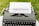 An old-fashioned typewriter holds a sheet of white paper with the word 'GHOSTING' typed in bold, capital letters. The typewriter is set outdoors on a grassy surface, creating a vintage and literary atmosphere.