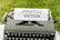 A vintage typewriter with a sheet of paper displaying the text 'DIGITAL DETOX' set against a backdrop of green grass.