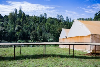 A panoramic view of Yovi Industries' manufacturing facility nestled in the green hills of Kullu, with tents being assembled outdoors.