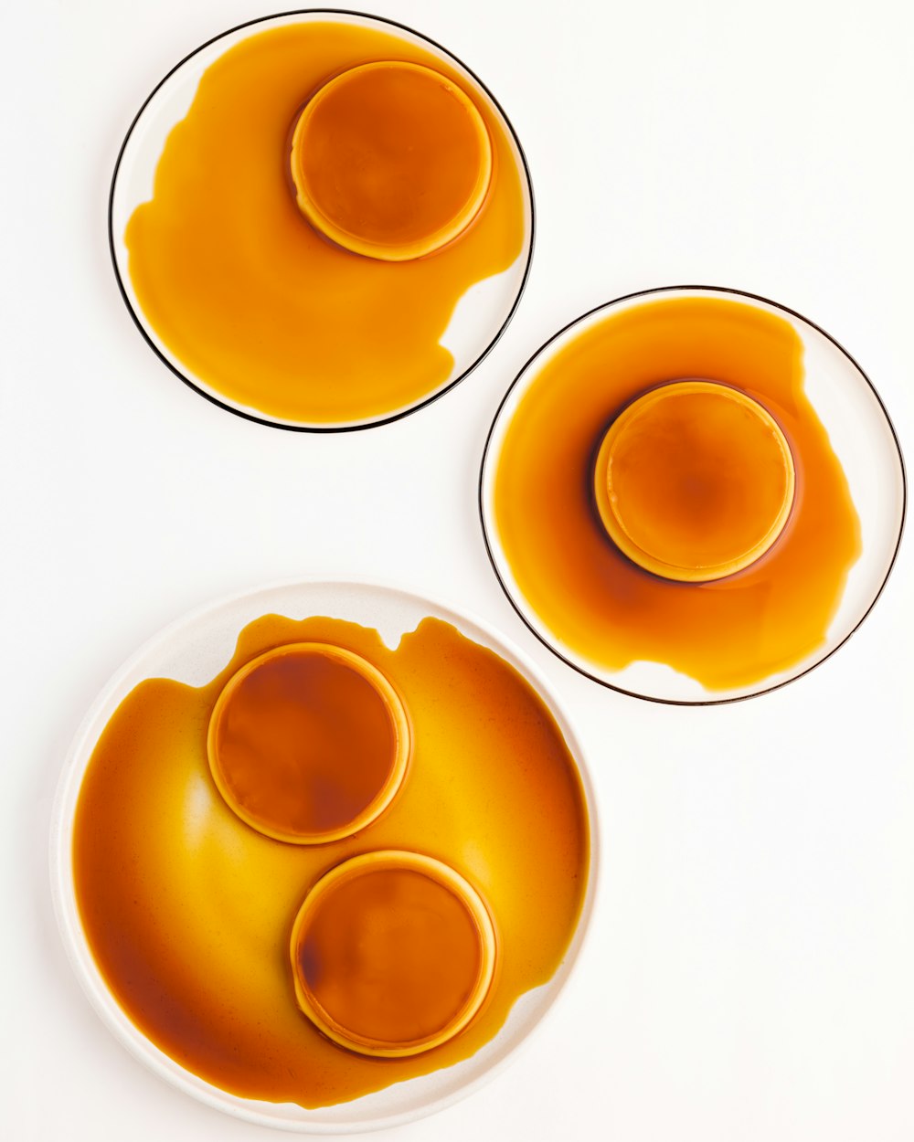 three plates of orange sauce on a white table