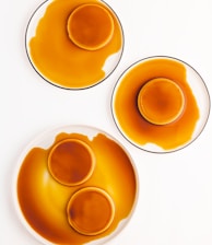 three plates of orange sauce on a white table