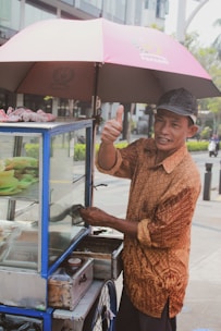 A cheerful vendor serving customers from a colorful food cart on a sunny day.