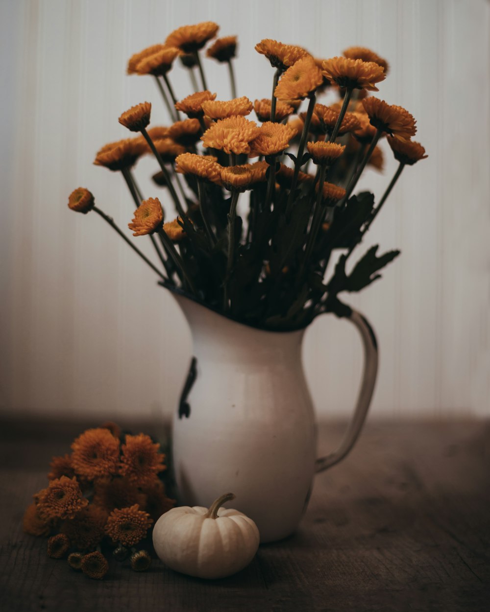 a white pitcher filled with lots of yellow flowers