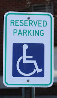 a handicapped parking sign on a pole in front of a building