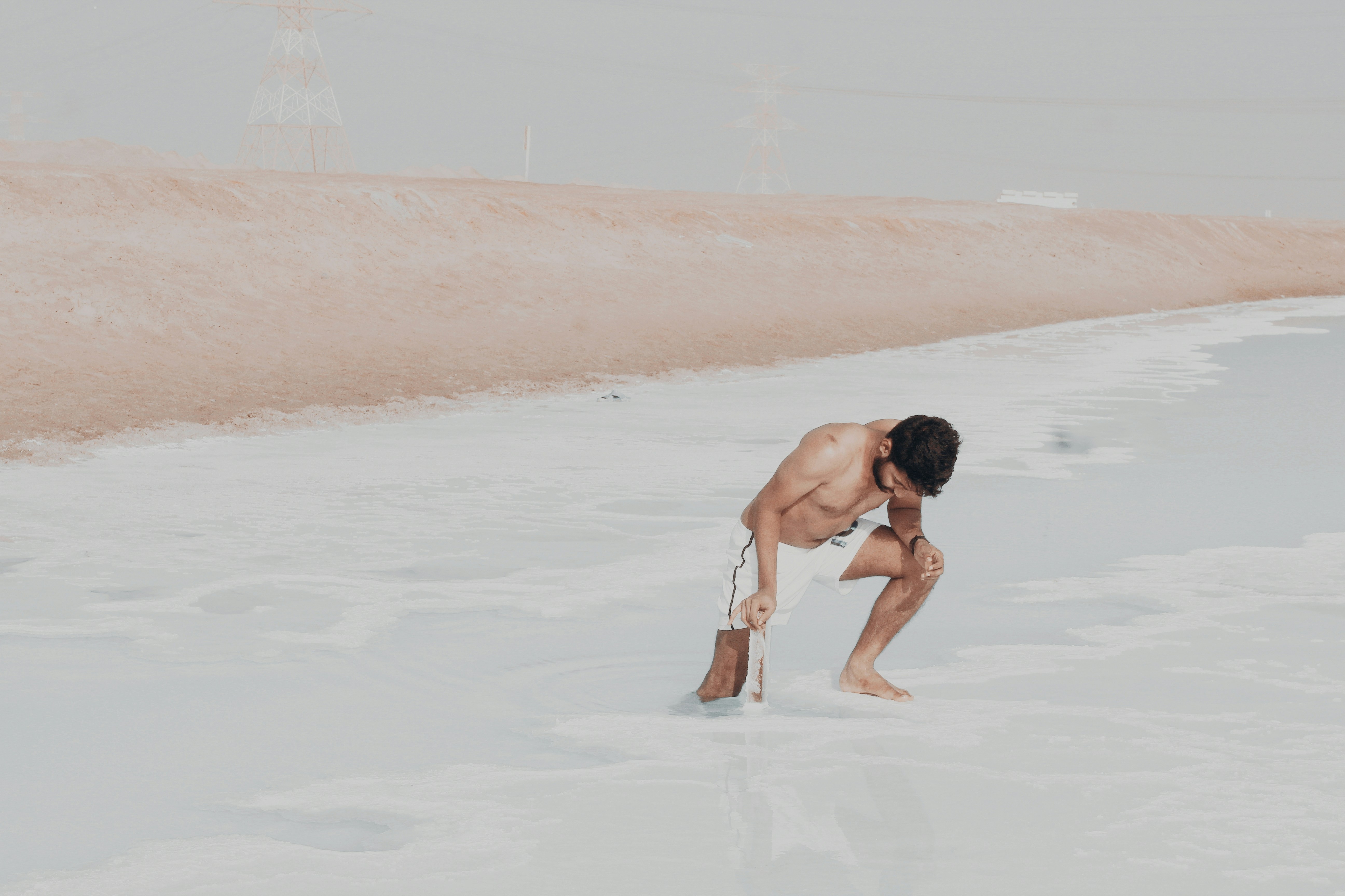 a man kneeling down on a beach next to the ocean