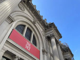 A stately academic building entrance framed by deep crimson banners symbolizing leadership and prestige.