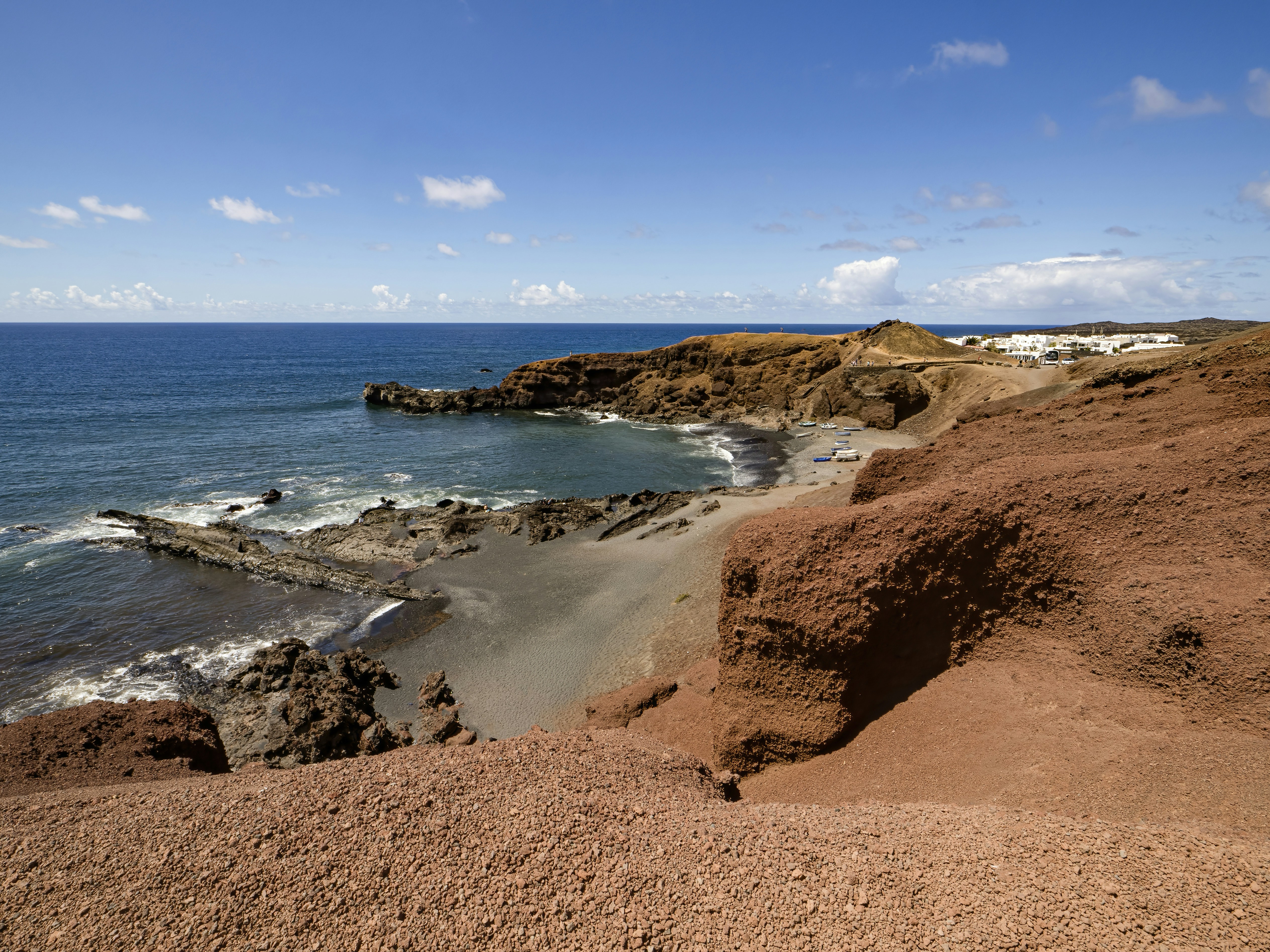 a sandy beach next to the ocean under a blue sky
