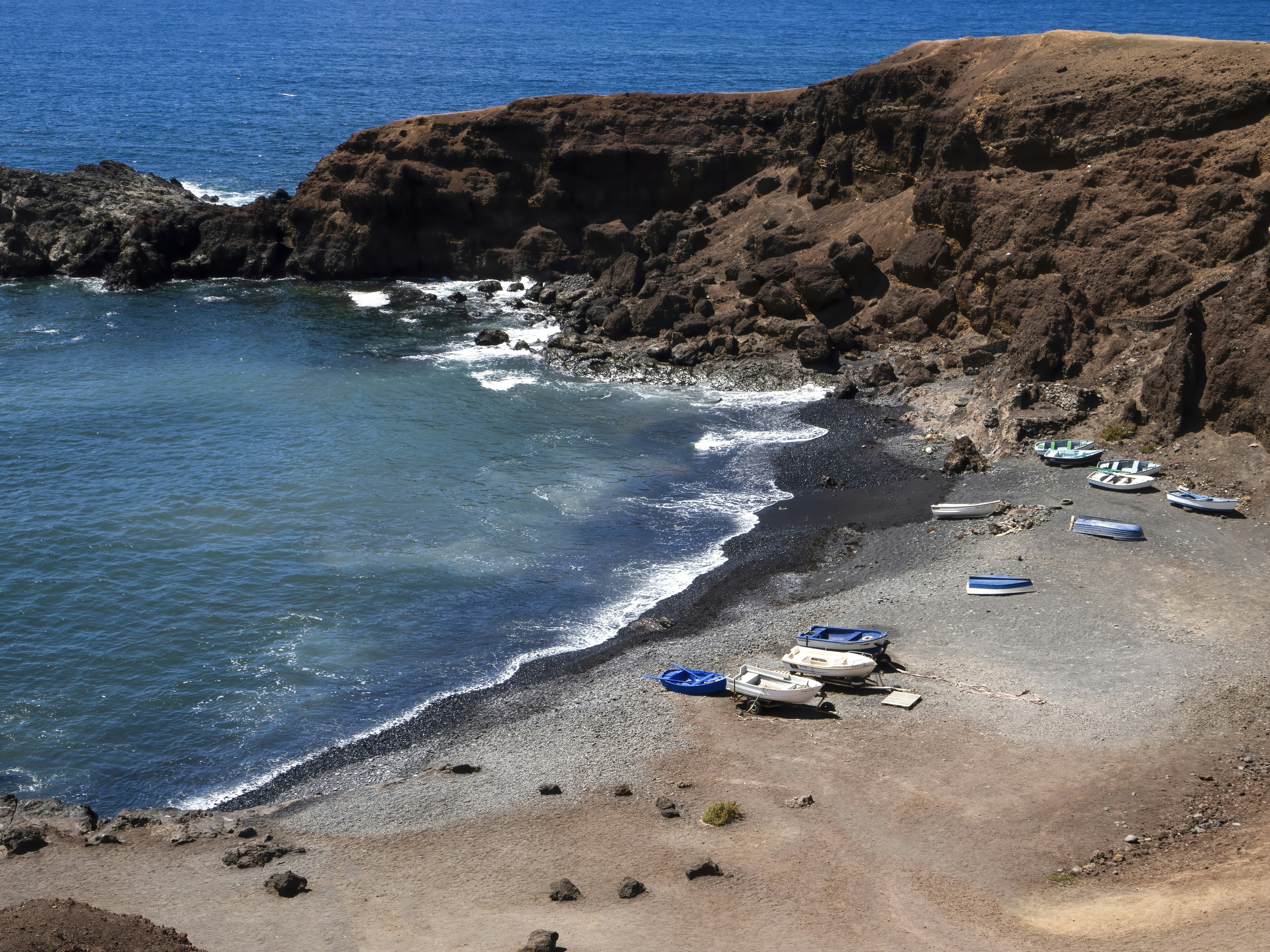 a group of boats sitting on top of a beach next to the ocean, 