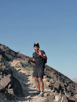 A young man hiking a scenic trail, confidently monitoring his glucose with Glucovita's CGM.