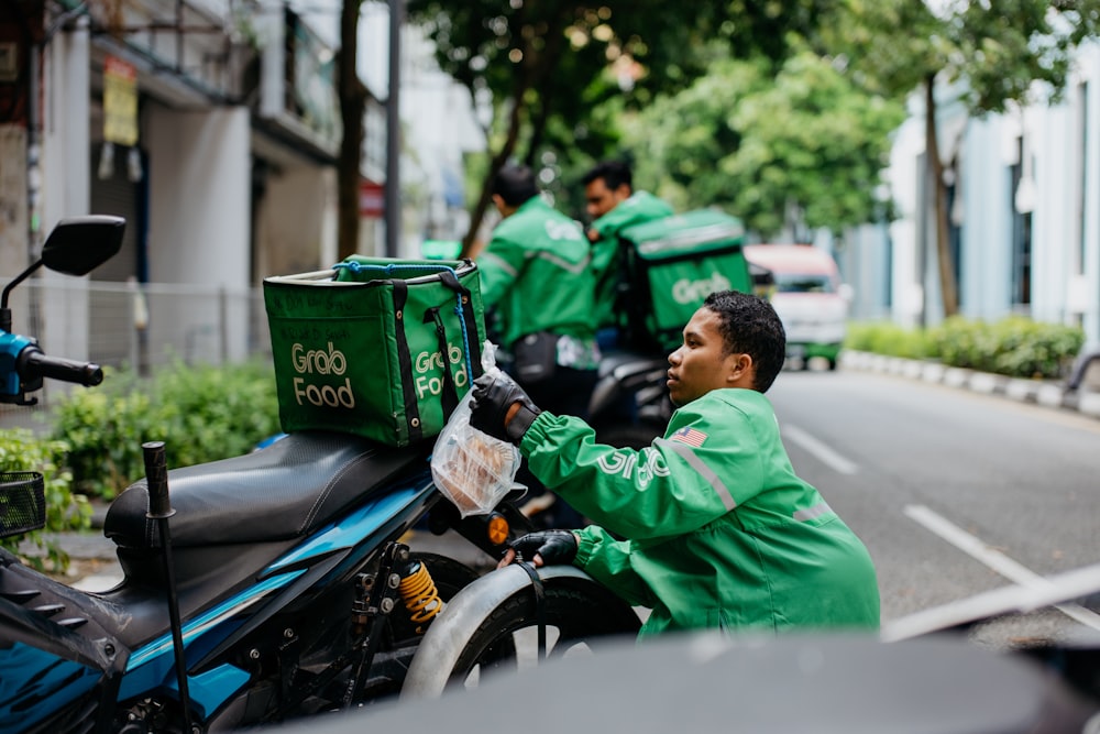 a man in a green jacket sitting on a motorcycle