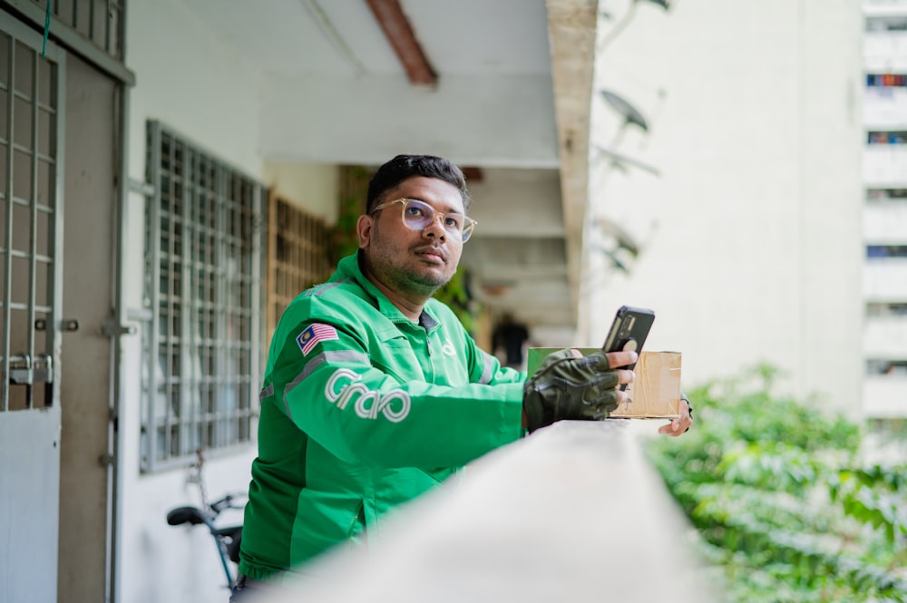 a man in a green jacket holding a cell phone