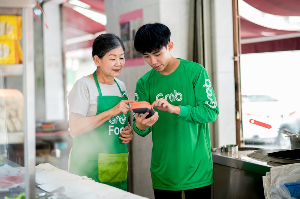 Un homme et une femme en chemise verte regardant un téléphone portable