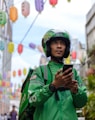 a man in a green jacket and helmet looking at a cell phone