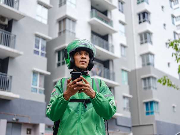 a man in a green jacket holding a cell phone