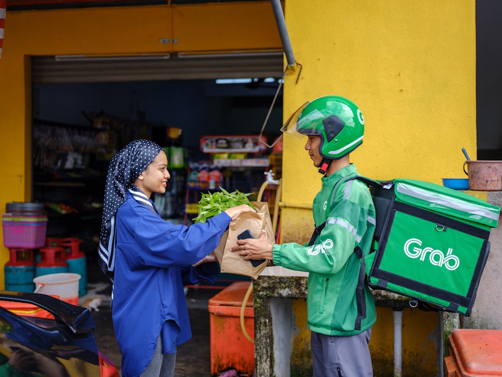 a man handing a bag of lettuce to a woman