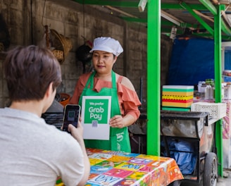 a woman holding a sign in front of a food stand