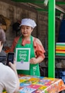 a woman holding a sign in front of a food stand