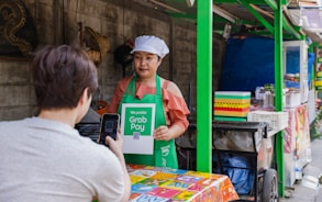 a woman holding a sign in front of a food stand