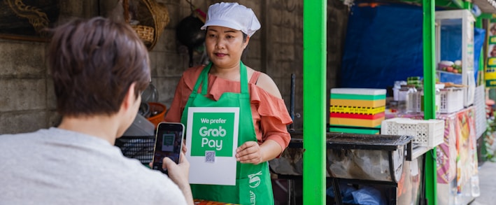 a woman holding a sign in front of a food stand