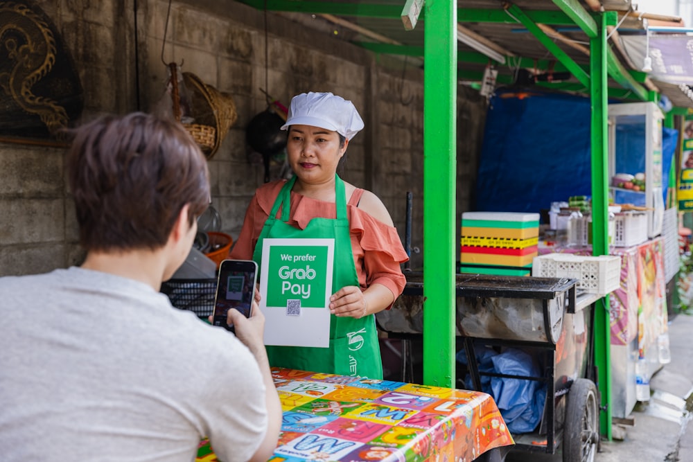 a woman holding a sign in front of a food stand