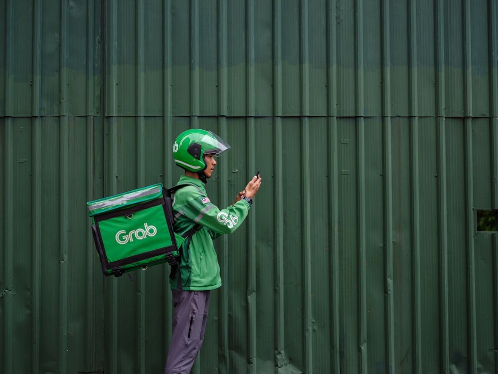 a man in a green jacket is holding a green bag