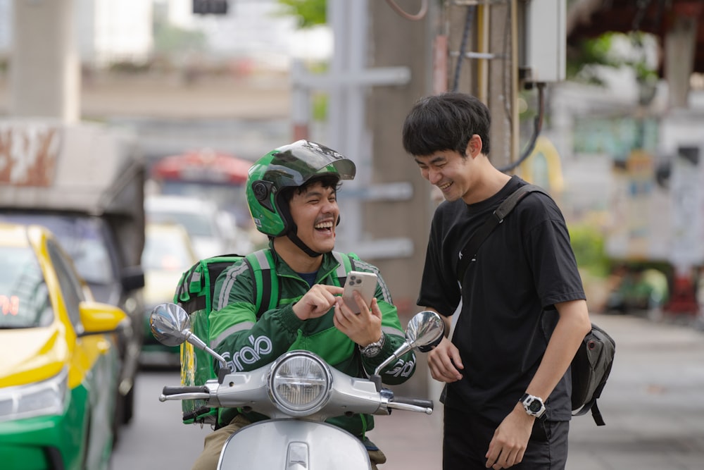 Un homme en veste verte sur un scooter regardant une cellule