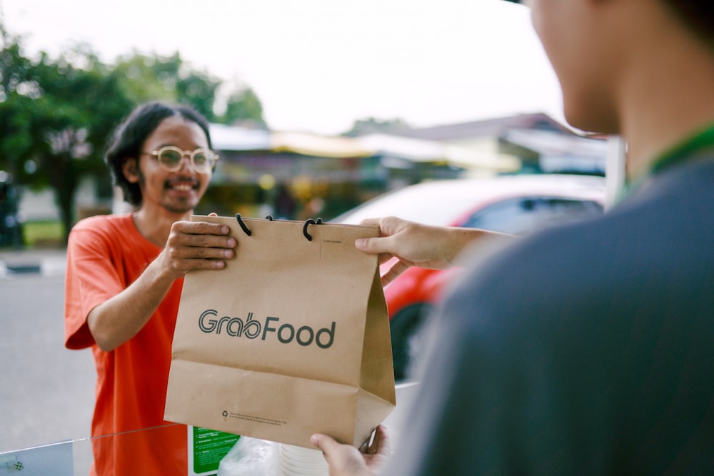 a man holding a paper bag with the word good food on it