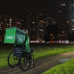 a person riding a bike with a green box on the back of it