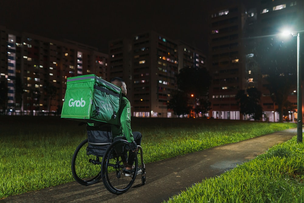 una persona montando una bicicleta con una caja verde en la parte posterior de la misma